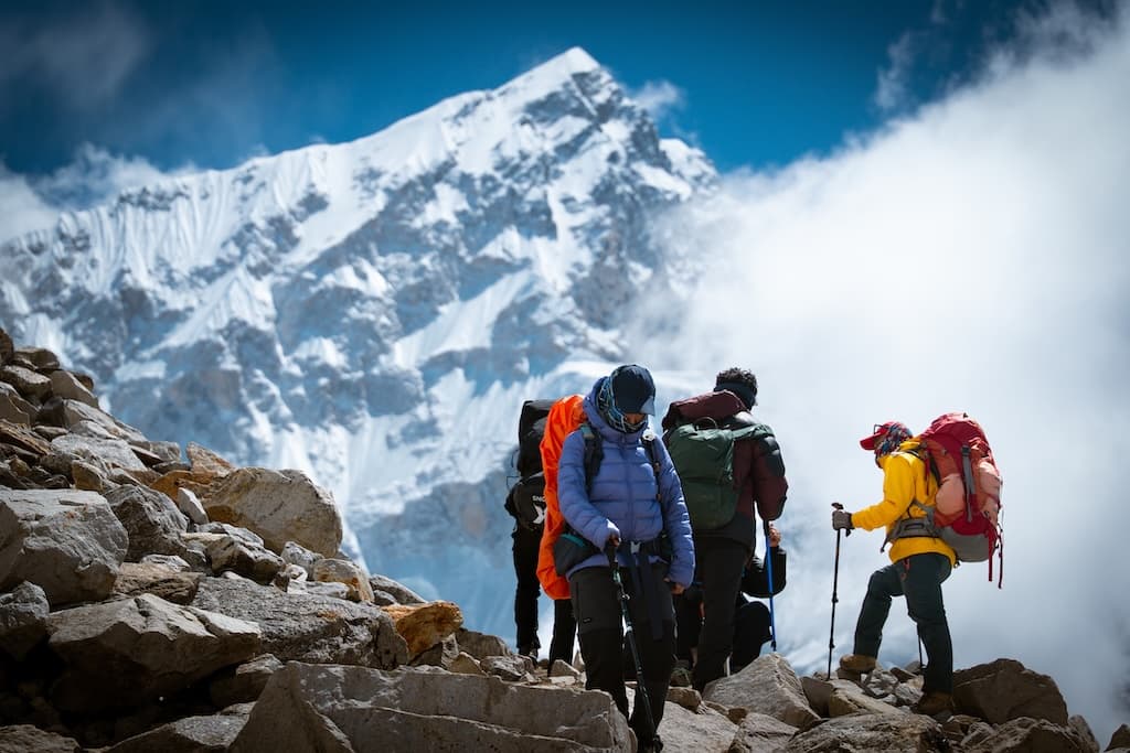 Group of trekkers standing on a mountain ridge at sunrise